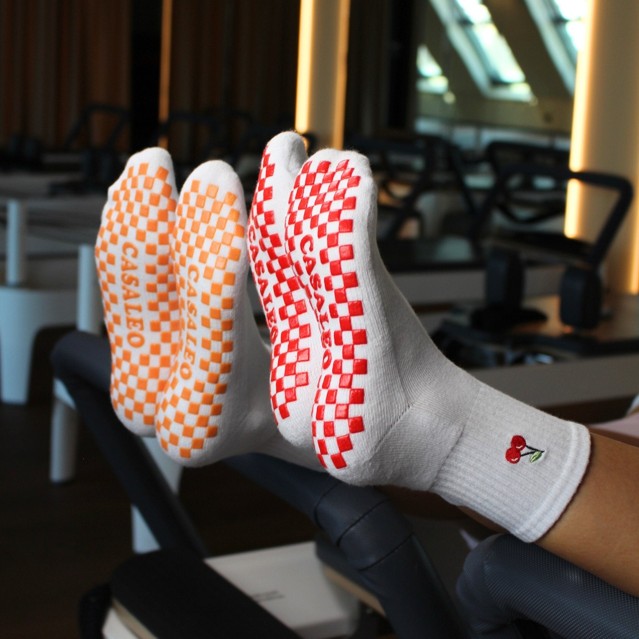 CASALEO Grip Socken mit roter Grip Sohle und Kirsch Icon und orangener Grip Sohle auf dem Reformer Gerät