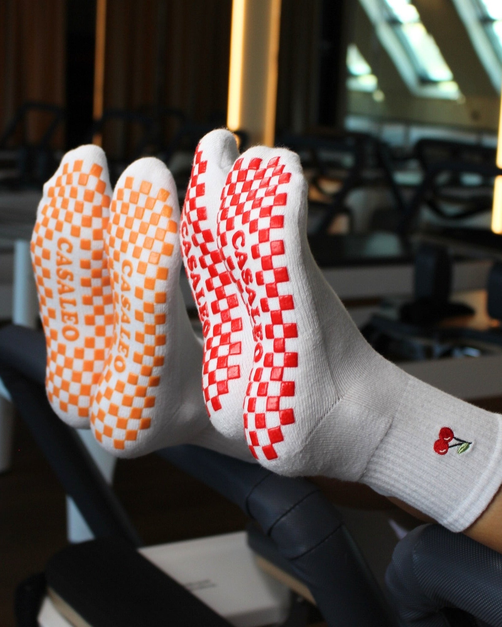 CASALEO Grip Socken mit roter Grip Sohle und Kirsch Icon und orangener Grip Sohle auf dem Reformer Gerät