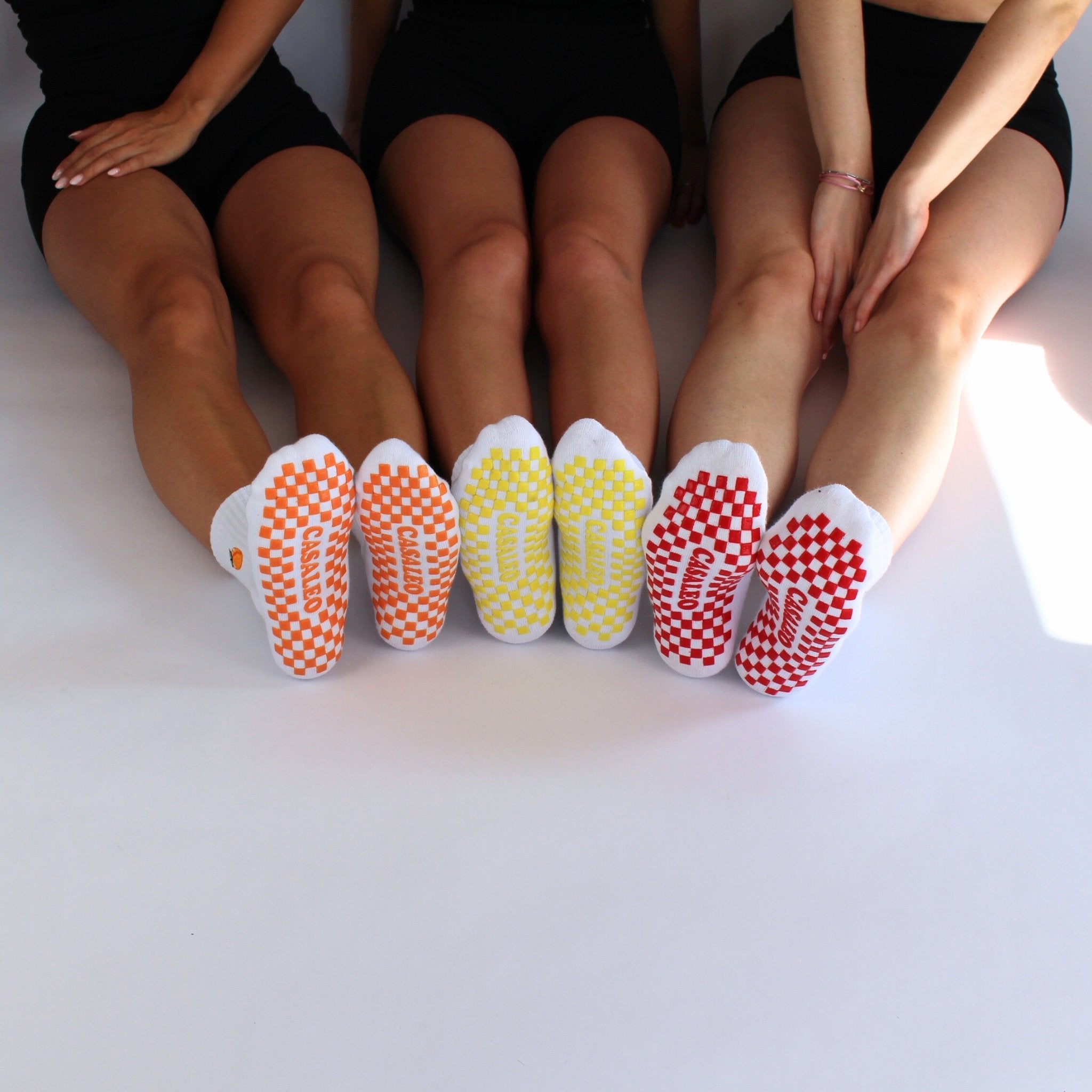 CASALEO Grip Socken mit roter, orangener und gelber Grip Sohle vor einer Fotoleinwand