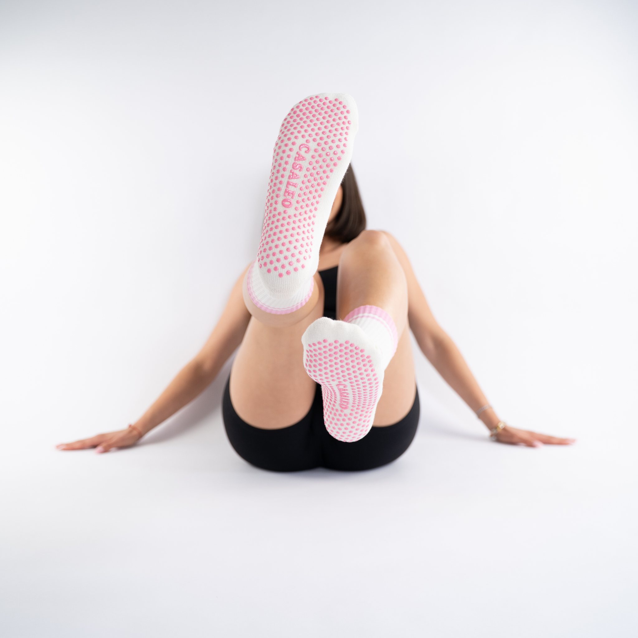 Model streckt pinke CASALEO Grip Socken Sohle in einem Fotostudio in die Kamera