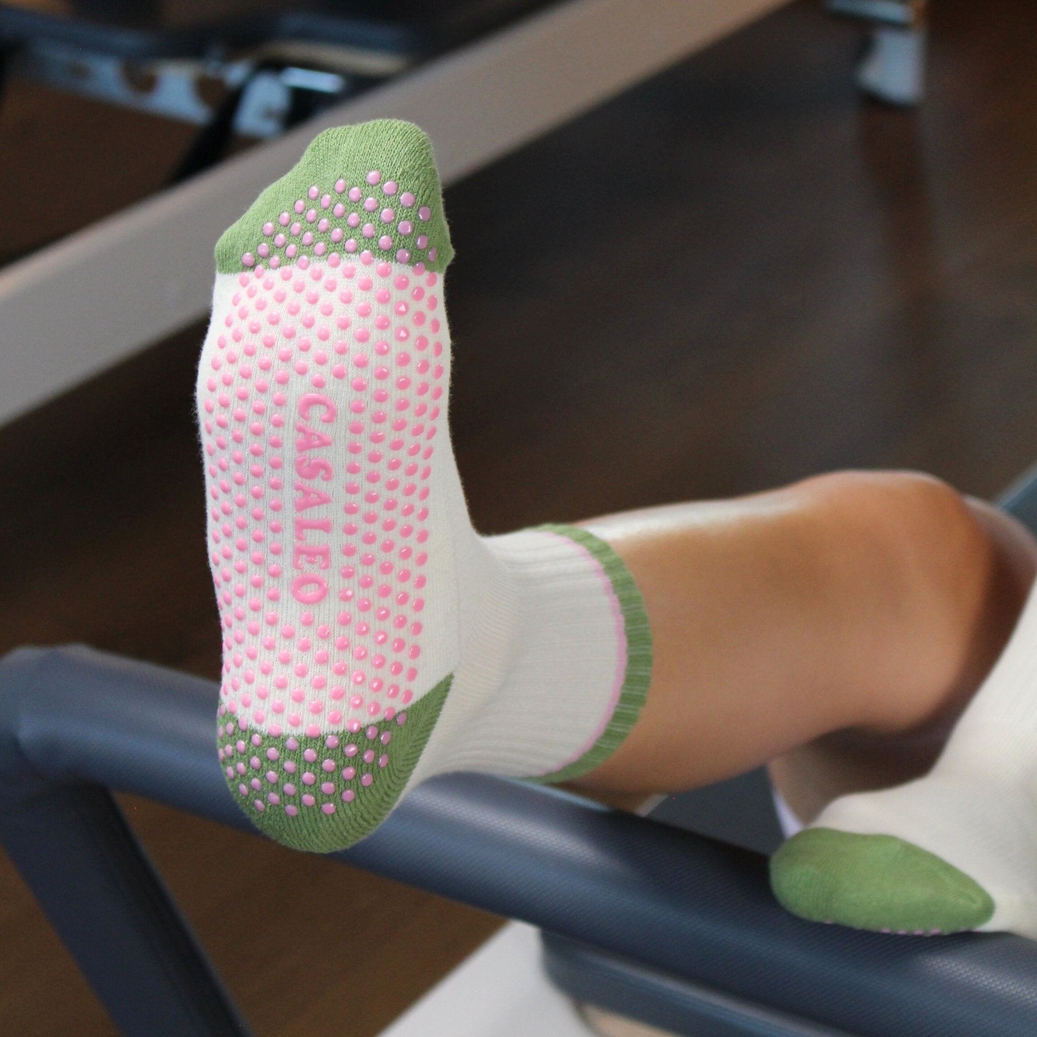 CASALEO Grip Socken in Oatmilk Weiß mit Streifen in Grün und Pink, auf dem Reformer Gerät von vorne
