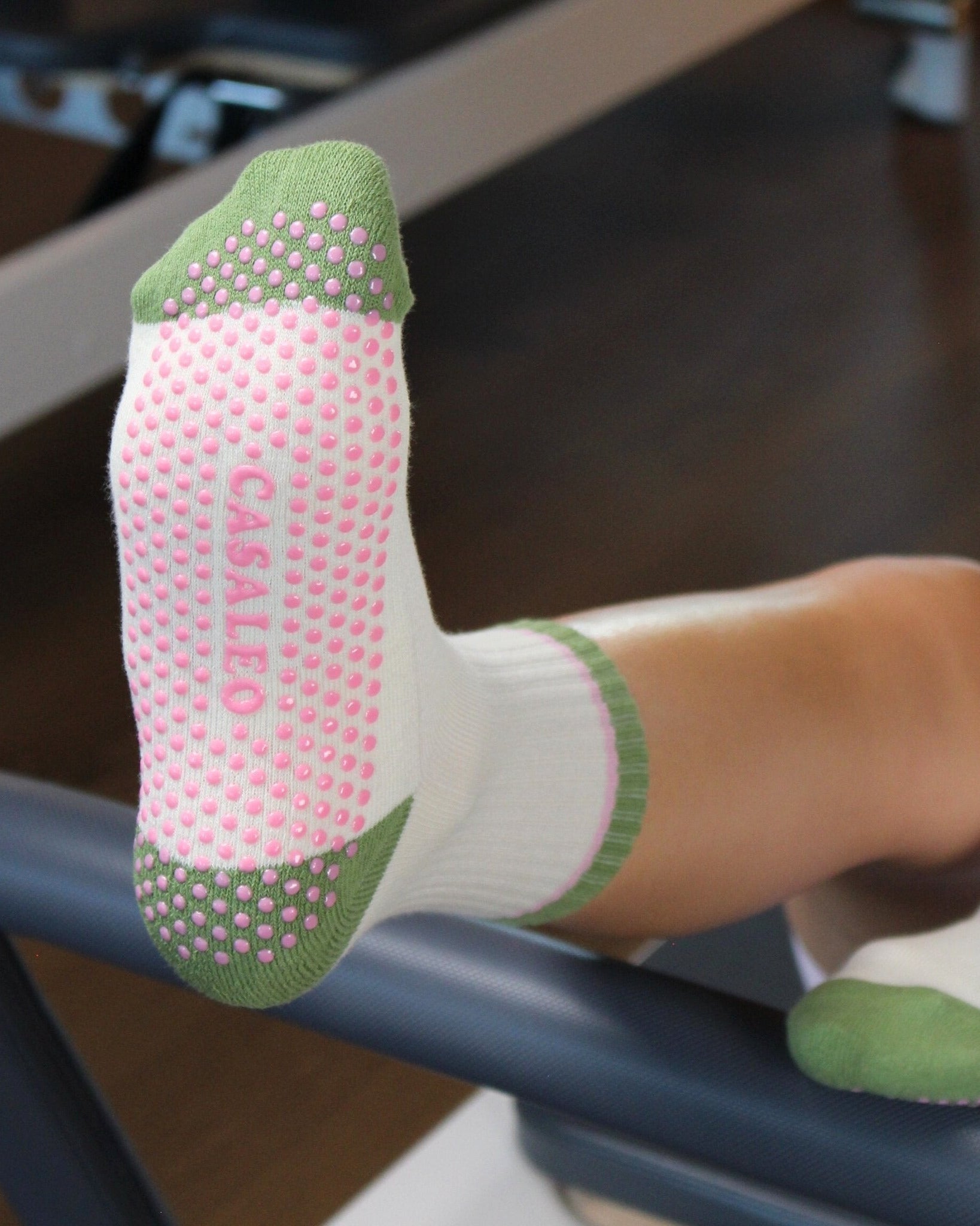CASALEO Grip Socken in Oatmilk Weiß mit Streifen in Grün und Pink, auf dem Reformer Gerät von vorne