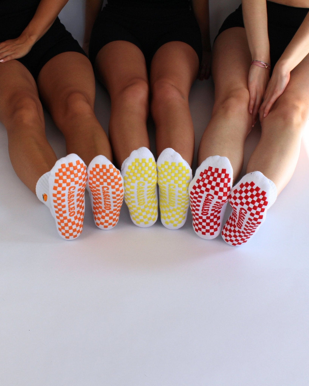 casaleo Grip Socken mit roter, orangener und gelber Grip Sohle vor einer Fotoleinwand