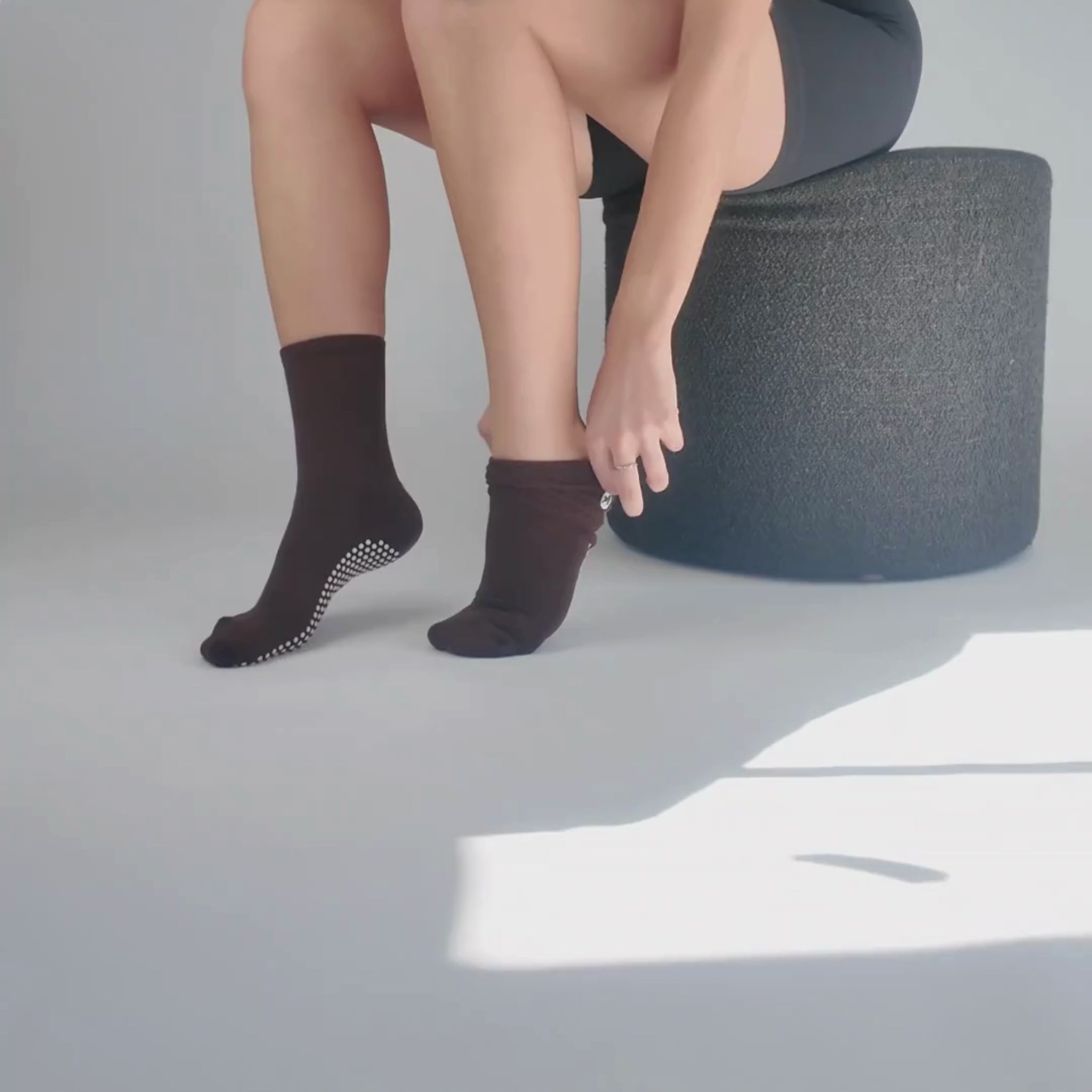CASALEO Grip Socken in Espresso Braun beim Anziehen vor der Foto Leinwand